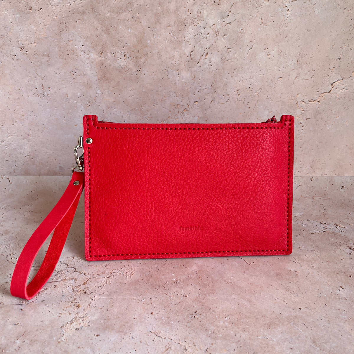 vue de face grande pochette avec dragonne en cuir rouge maroquinerie faméthic